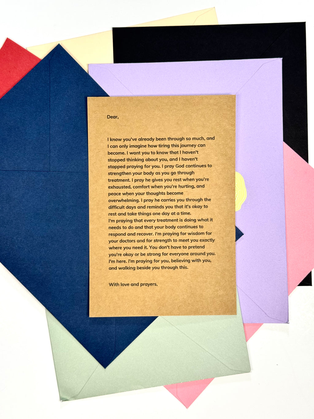 A printed sympathy card with black text on a tan cardstock background, layered on top of multiple colored envelopes or folded paper sheets in red, yellow, blue, purple, pink, and green on a white background.