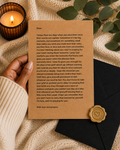 A square parchment-style card with printed condolence text, styled on a dark envelope with a gold wax seal, beside a lit candle and green leaves on a textured cream fabric background.