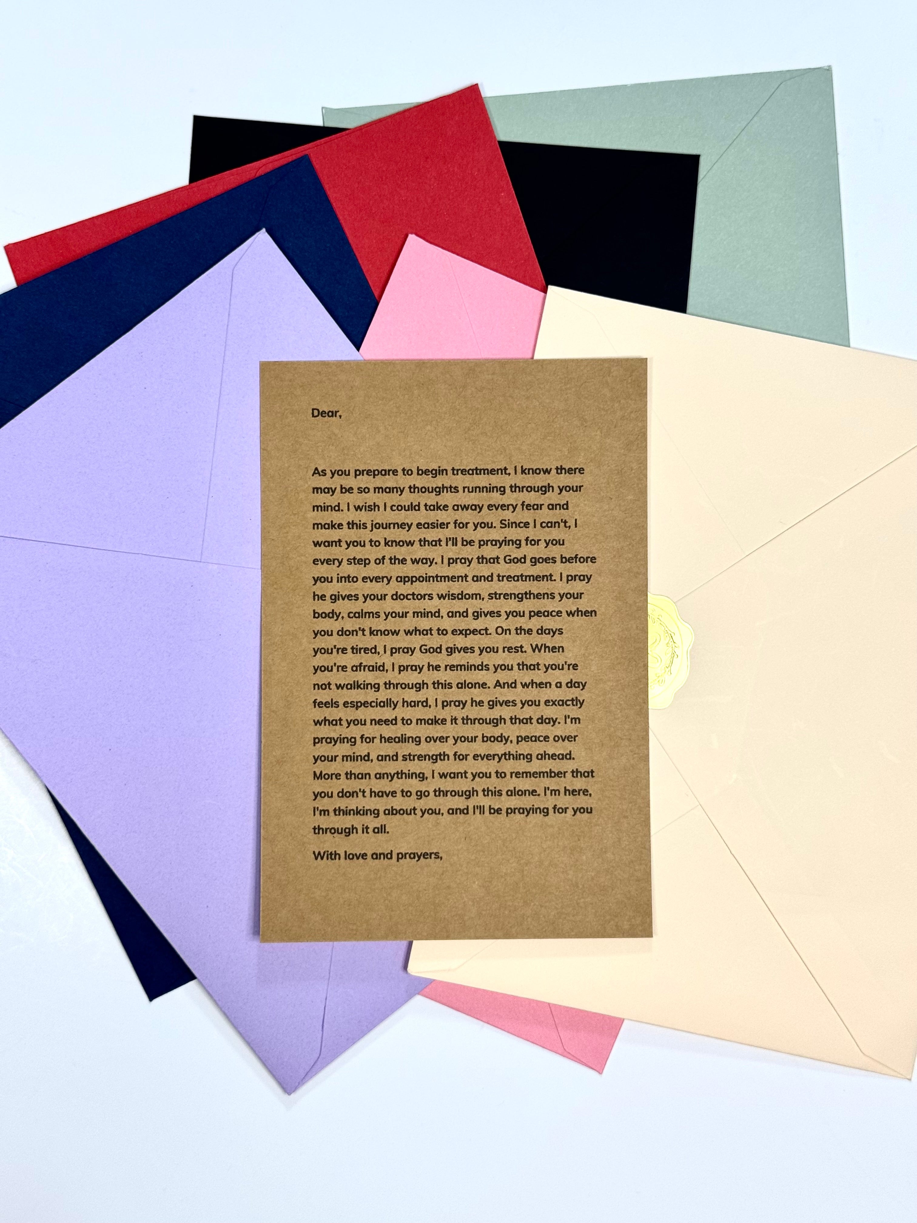 A printed sympathy or bereavement card with a brown parchment-style text body, shown fanned over several colored envelopes on a light blue background.
