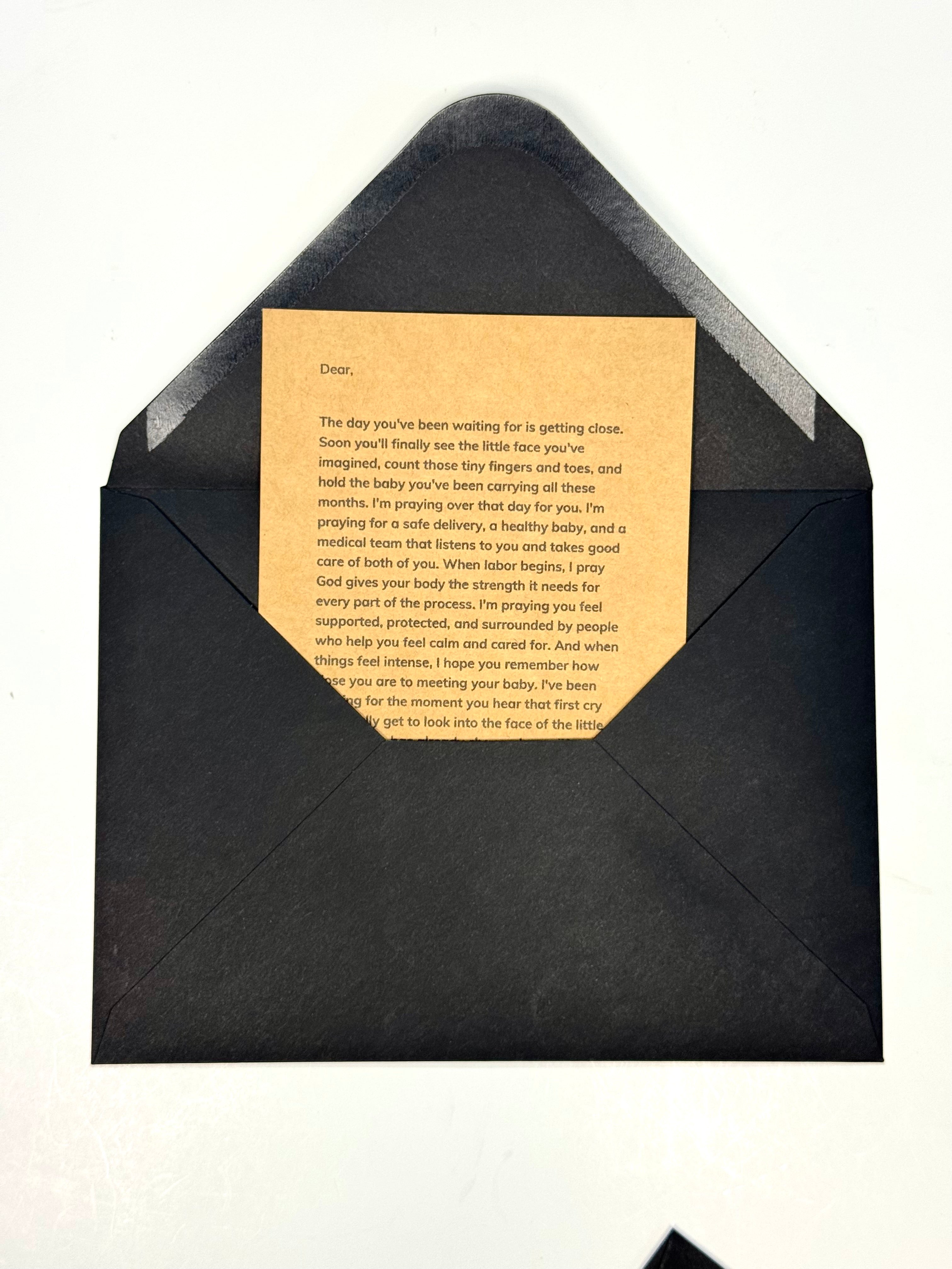 A black envelope with a gold-toned card inside, photographed from above on a plain white background.