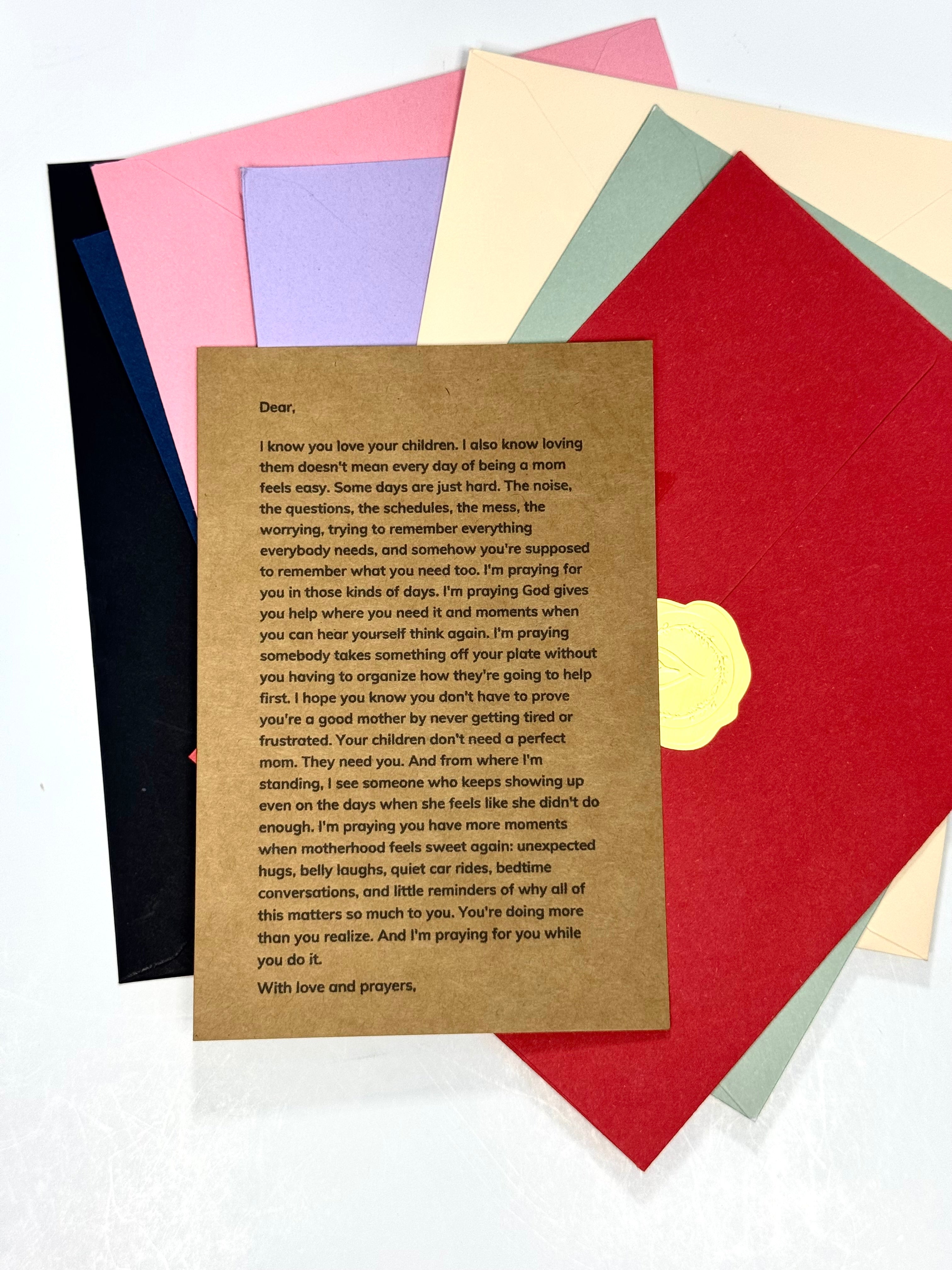 A square kraft paper card with printed condolence text, placed on top of a fan of colored paper sheets in red, pink, blue, green, yellow, and black.