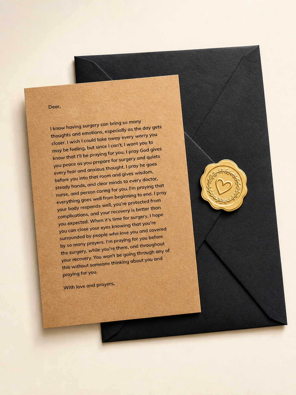 A black envelope with a gold wax seal sits on a beige surface next to a brown kraft paper card containing a printed message, photographed from above.