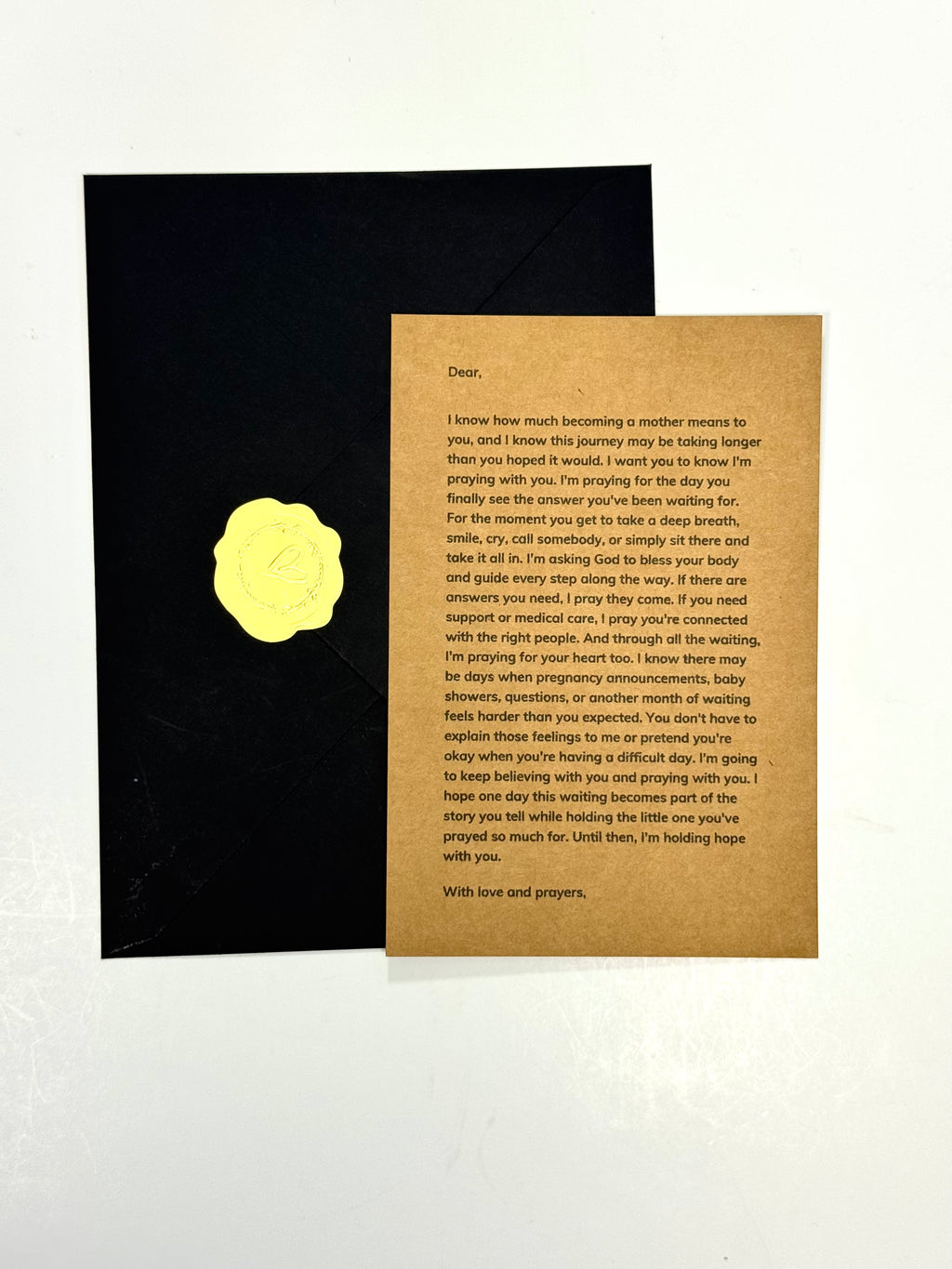 A sympathy or condolence card set featuring a textured brown kraft paper message card with a gold wax seal, displayed next to a black envelope on a white background.