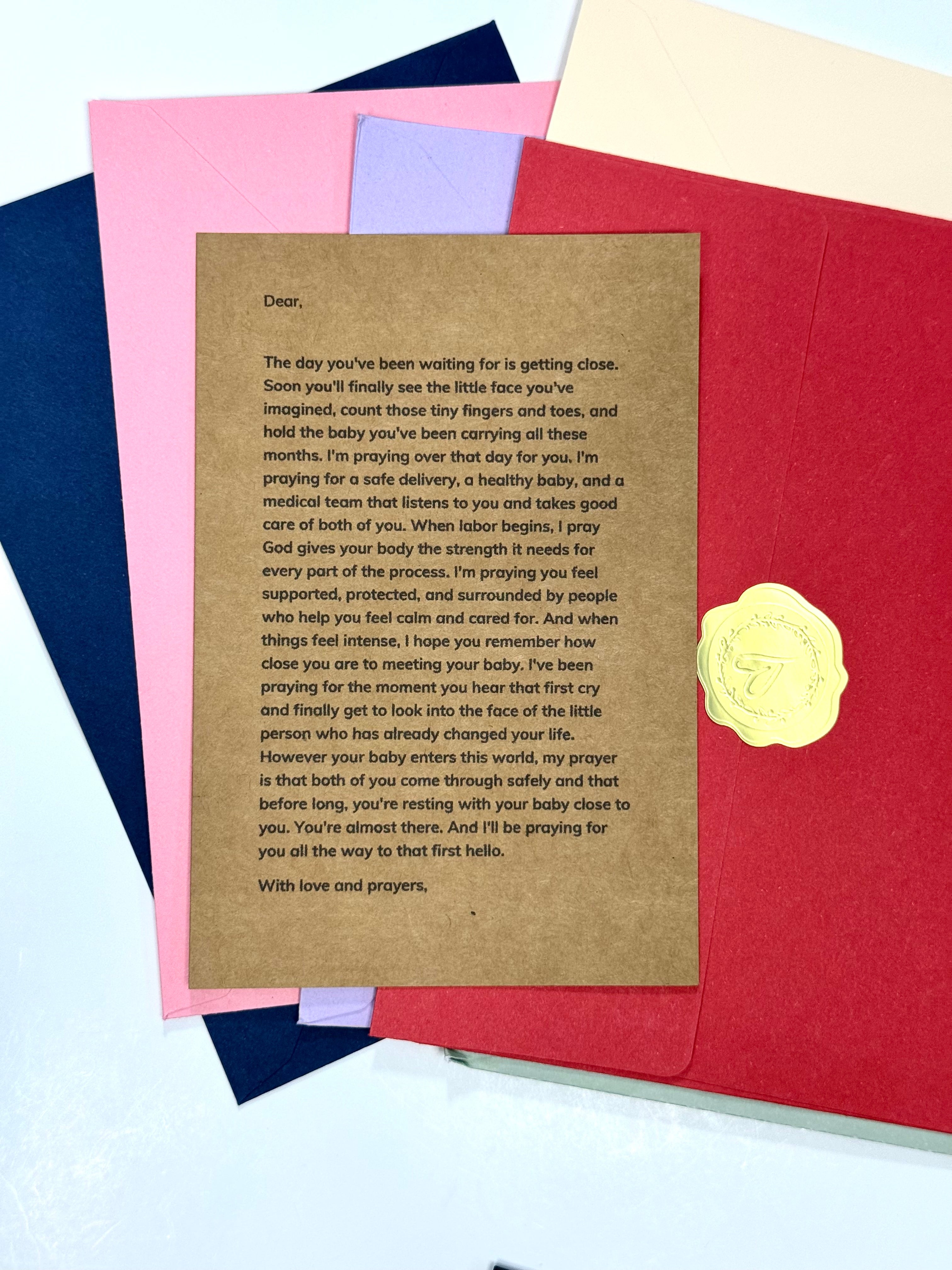 A printed sympathy or remembrance card with a brown kraft-paper style body and a gold embossed seal, shown layered over red, pink, and navy envelopes on a light background.