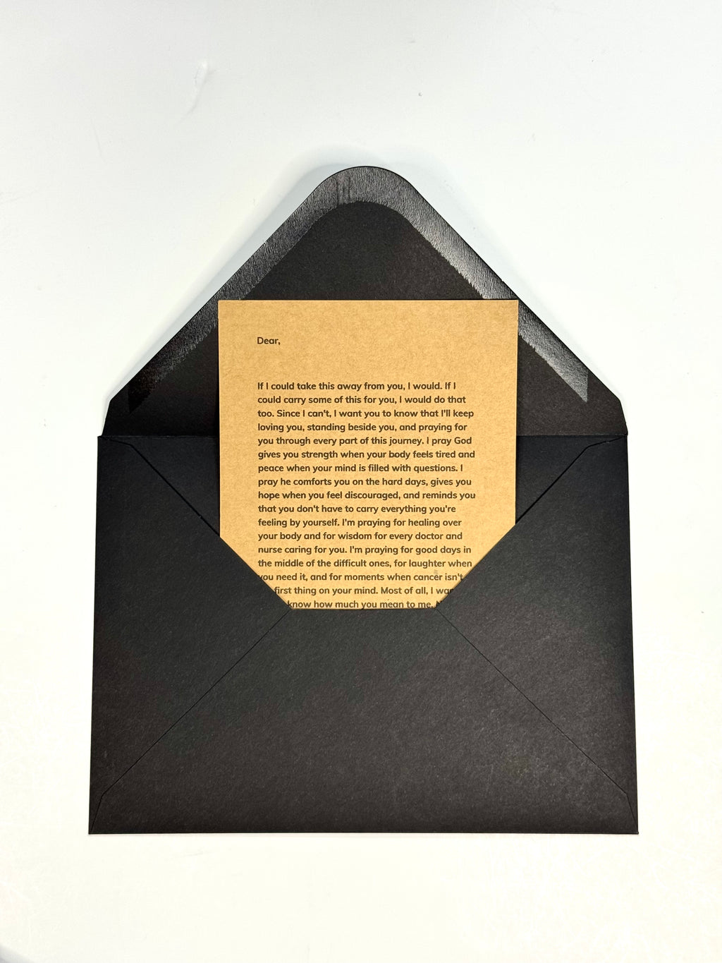 A black envelope with a beige letterhead card inserted, photographed from above on a plain white background.