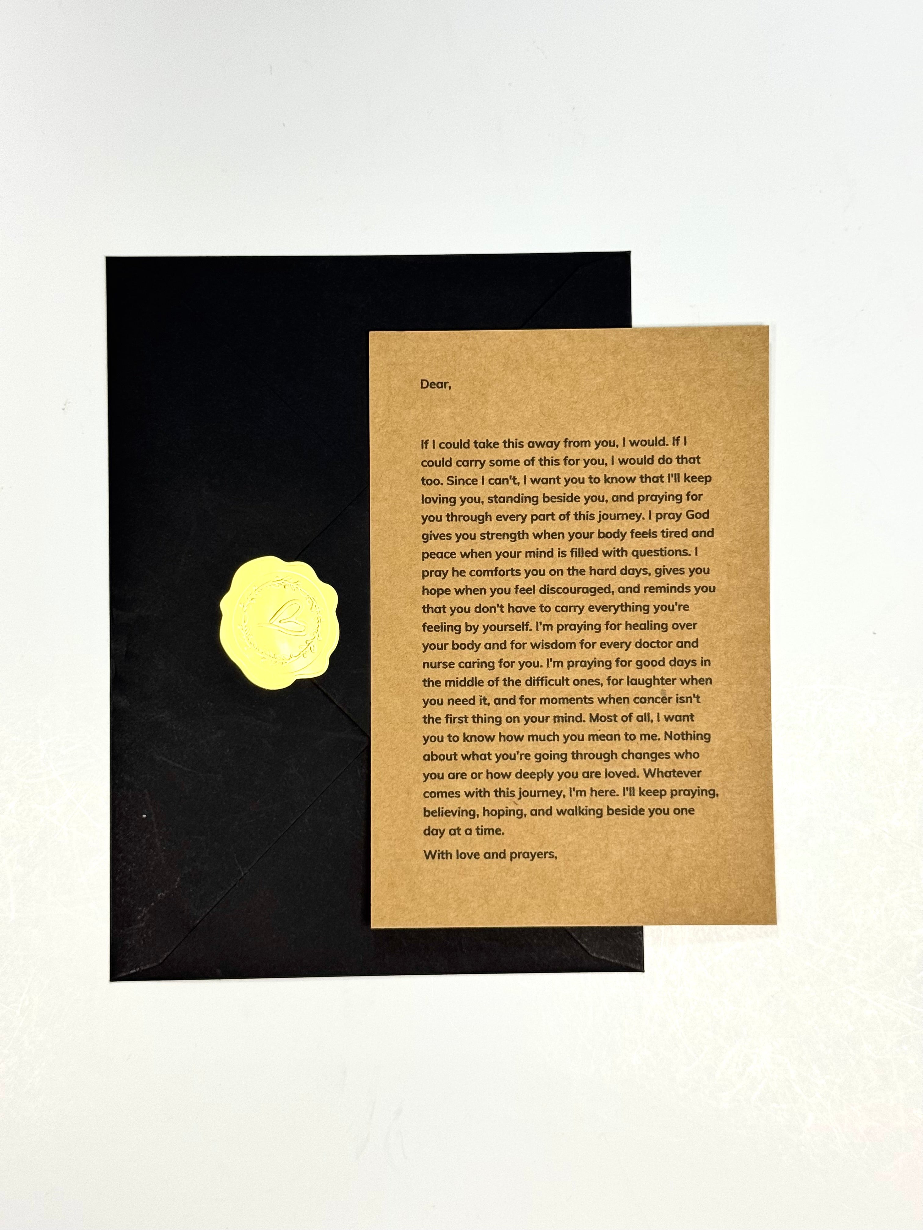 A square letter card with printed text on a tan background, placed on top of a black envelope against a white studio background. A circular yellow sticker is visible on the left side of the card.