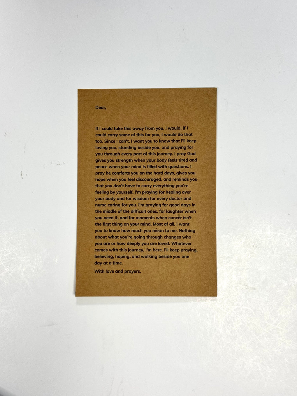 A rectangular brown card with printed black condolence text, photographed against a white textured wall.